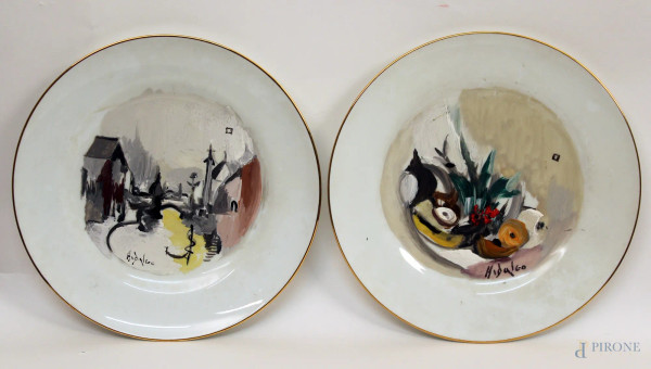 Coppia di piatti da muro in porcellana Ginori dipinti a soggetto di paesaggio e natura morta, firmato Hidalgo, diametro 24 cm.