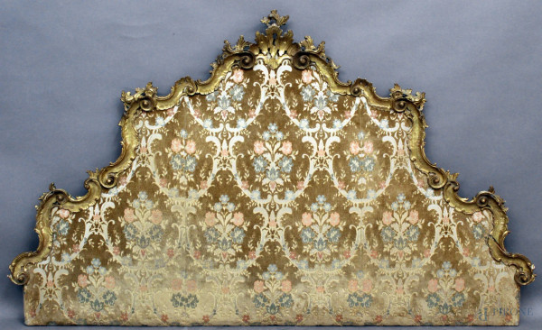 Testata da letto in legno dorato ed intagliato a volute e foglie d'acanto, tappezzeria in stoffa fiorata, XIX sec, h. 112x186 cm.