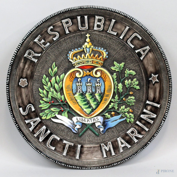 Grande piatto in maiolica dipinta raffigurante stemma della Repubblica di San Marino, dedica e firma alla base, diam. cm 56,6, XX secolo.