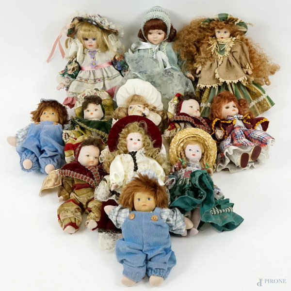 Lotto di dodici bambole in porcellana, vestiti in tessuto, alt. max cm 35, XX secolo.