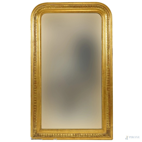 Specchiera in legno dorato di linea sagomata, XX secolo, decori incisi, battuta interna a perline, ingombro cm 121x71, (segni del tempo).