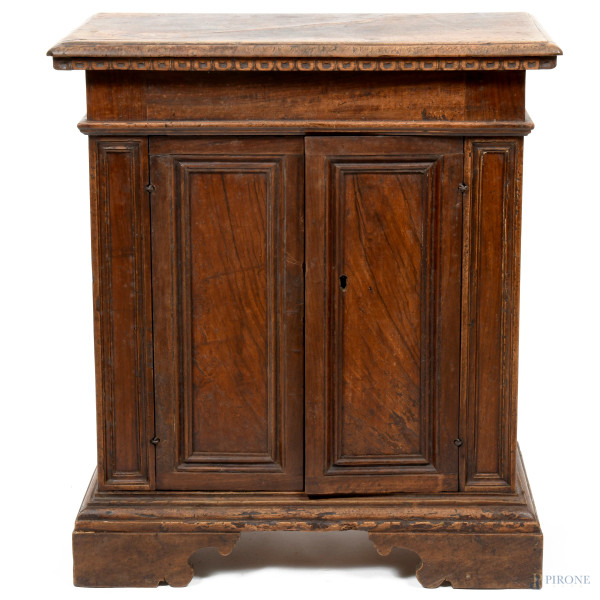 Credenzino di manifattura romano-umbra del XVI-XVII secolo in legno di noce modanato con fronte a doppio sportello e interno a doppia scaffalatura. Piano rettangolare con profilo intagliato, cm 79x70x36, (difetti)