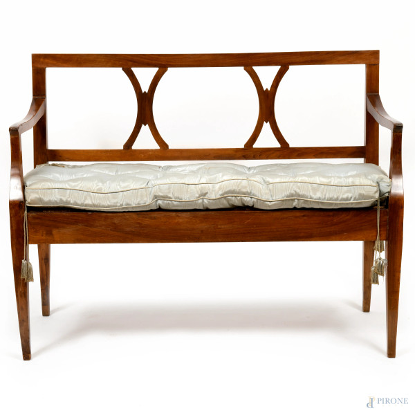 Panca con struttura in legno di noce con schienale a raffinata traforatura con motivi a doppia X incrociata. Braccioli leggermente ricurvi. XIX secolo, cm 92x118x48, (difetti)