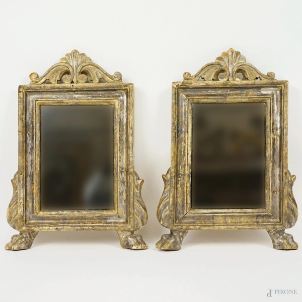 Coppia di specchiere in legno intagliato, laccato ed argentato, XIX secolo, cimasa intagliata ad acroterio,  poggianti su piedini zoomorfi, ingombro cm 39x26,  (difetti)
