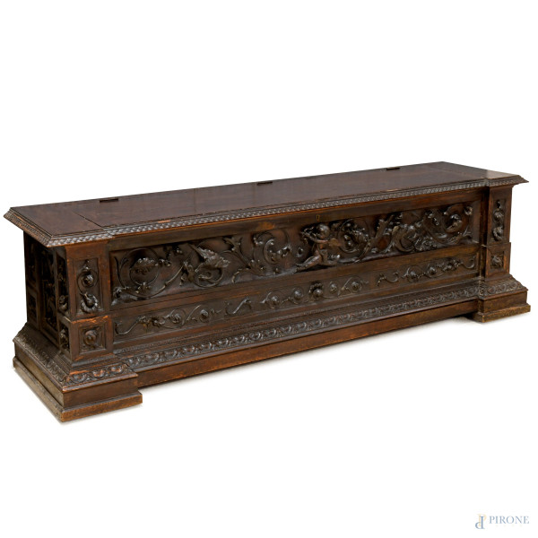 Cassapanca in noce tinta scuro riccamente intagliata con motivi a volute di ispirazione neorinascimentale, XX secolo, cm 51,5x185x45x5, (difetti)
