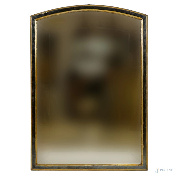 Specchiera di linea sagomata in legno ebanizzato e dorato, XX secolo, specchio molato, misure ingombro cm 102x72,5, (difetti).