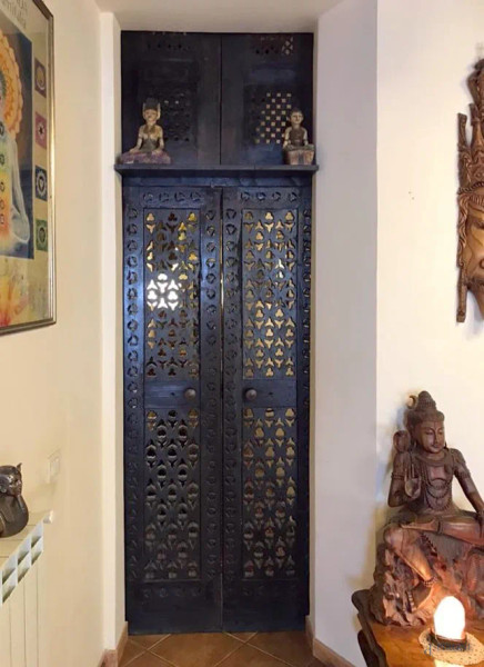 Porta in legno traforato ed ebanizzato, arte orientale, XX secolo, due ante cm h 210x44x6 cadauna, due pannelli cm 91x45x2,5 cadauno, (segni del tempo).