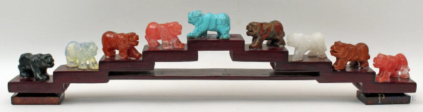 Lotto composto da nove sculture a soggetto di animali in pietre pregiate, poggianti su base in tek, Lunghezza 45 cm.