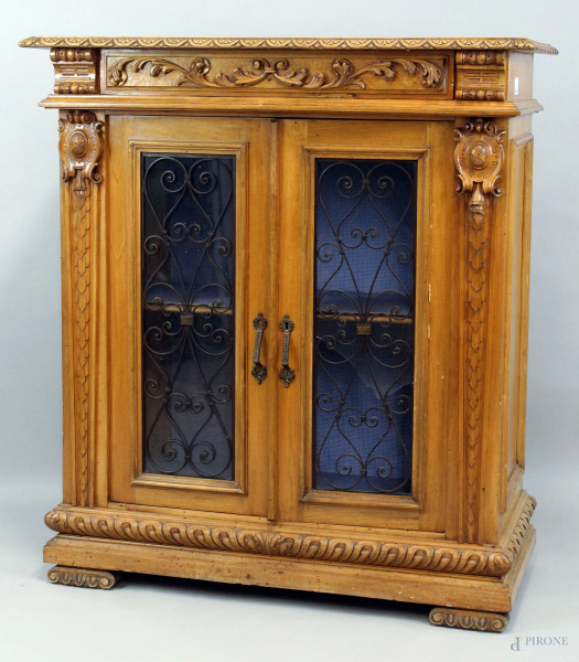 Credenza in legno chiaro ad un cassetto e due sportelli a vetri con decori in ferro forgiato, particolari intagliati, fine XIX secolo, cm h 113x100x47