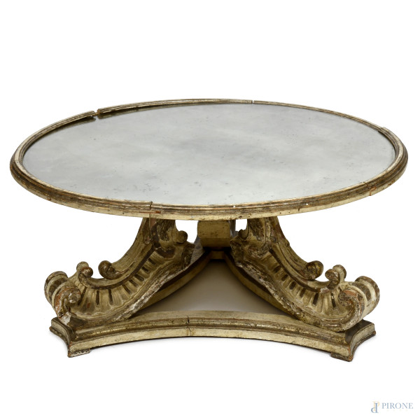 Tavolo basso con piano circolare a specchio e struttura legno intagliato, laccato e dorato poggiante su tre gambe a ricciolo, XX secolo, cm 53,5x110, (mancanza del piano, segni di usura, scalfiture, rotture, restauri, difetti)