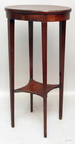 Tavolino d&#39;appoggio di linea ovale in mogano a due piani retto da quattro colonne, h. 75x34x30 cm.
