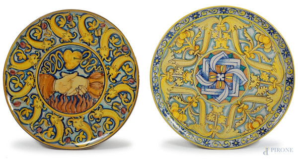 Lotto di due grandi piatti da muro in maiolica dipinta, XX secolo, decori raffiguranti soggetti diversi, diam. cm 53