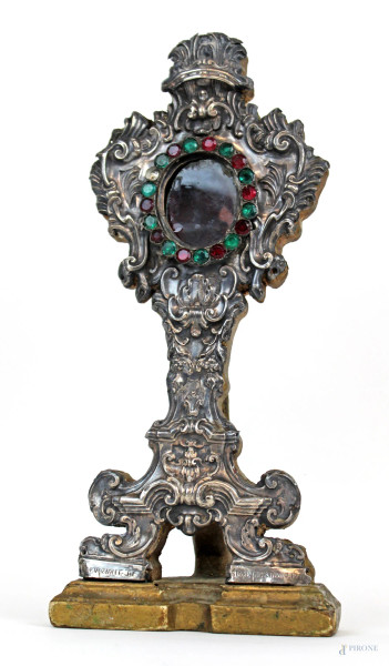 Reliquario del XVIII secolo, in legno rivestito in lamina d'argento sbalzata e cesellata a motivi di rocailles con applicazioni in vetro colorato, cm h 34,5, (difetti).