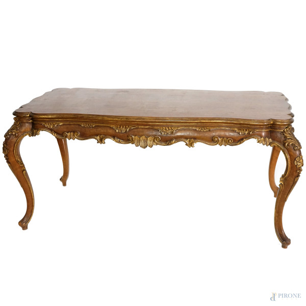 Tavolo in noce stile Luigi XV con piano rettangolare dal profilo centinato, fascia sottostante il piano, gambe di linea mossa intagliate a volute e motivi vegetali dorati, cm 73x157x71