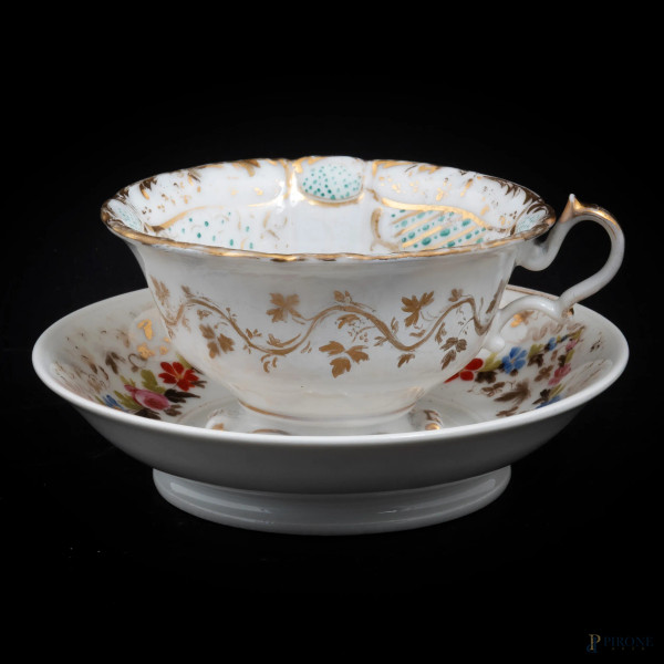 Lotto composto da una tazza e da un piattino in porcellana nei toni del bianco e dell'oro con decori a motivi floreali, XX secolo, altezza cm 8, diametro cm 17,5, (segni di usura, rotture, restauri)