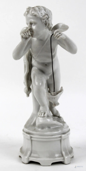 Amorino con lucerna in porcellana bianca, altezza cm. 20, manifattira Capodimonte, XX secolo.