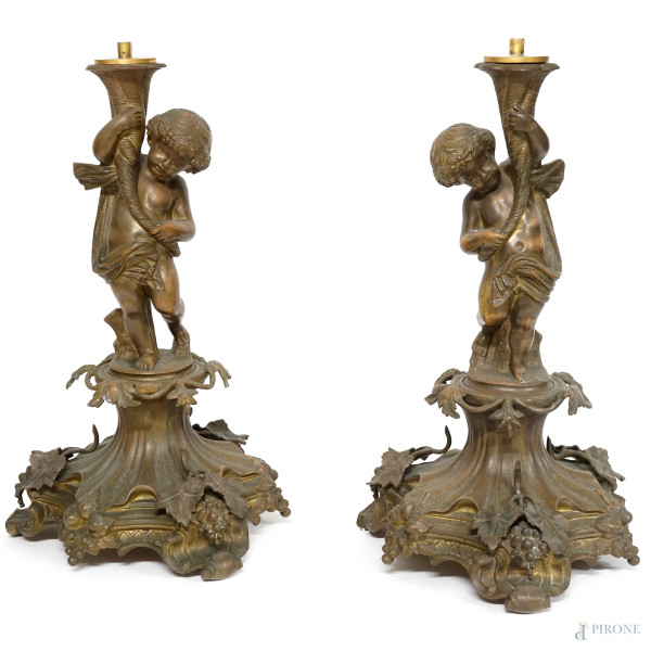 Coppia di candelieri in bronzo con fusto a foggia di putto e binet caratterizzato da un movimento a spirale, poggiante su tre piedini, decori a motivi vegetali, XX secolo, altezza cm 45.5