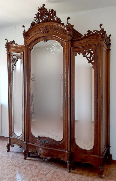 Armadio a tre ante a specchi in noce intagliata a motivi di foglie d&#39;acanto, con cassetti all&#39;interno, XIX secolo, altezza 298x210x60 cm.