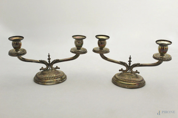 Coppia di candelieri a due luci in argento cesellato, gr. 440, h. 13 cm.