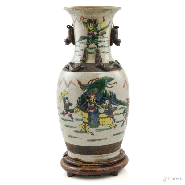 Vaso in porcellana decorato in policromia con scene di guerra e rilievi in finto bronzo su base in teak. Cina XX secolo, altezza cm 35, (segni di usura, sbeccature, difetti di cottura)
