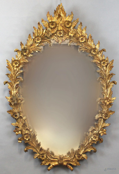 Specchiera di linea ovale in legno intagliato e dorato a motivi di foglie e fiori, XX secolo, cm h 123x86