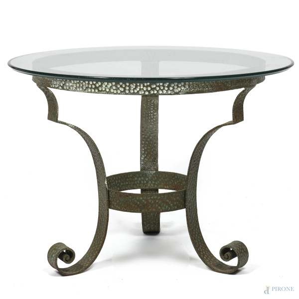 Tavolino con piano in vetro e struttura in ferro battuto terminanti a tre gambe a ricciolo raccordate, XX secolo, altezza cm 65, diametro cm 90, (segni di usura)