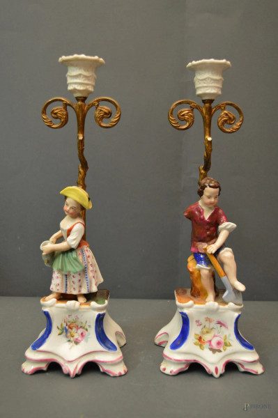 Coppia candelieri ad una luce con fanciulli a rilievo in porcellana policroma, poggianti su basi periodo Luigi Filippo, (mancanze), h. 34 cm.