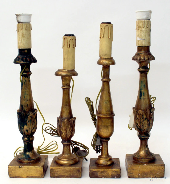 Lotto composto da quattro candelieri in legno dorato, h. max 36 cm.