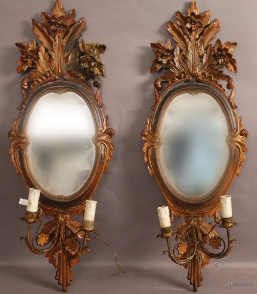 Coppia di specchierine montate ad appliques a due luci, in legno intagliato e dorato, primi &#39;900, H 75 cm.