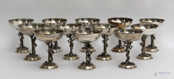 Lotto composto da dodici coppe in argento rette da figure femminili.
