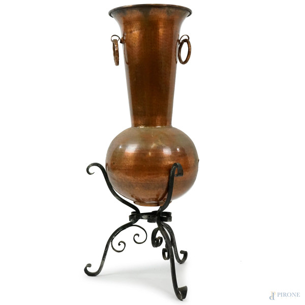 Grande vaso in rame, poggiante su base in ferro battuto a tre gambe desinenti a ricciolo, metà XX secolo, cm h 83x38