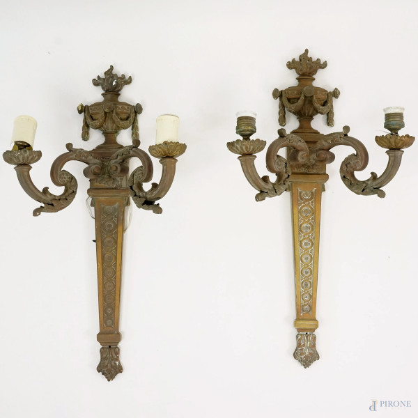 Coppia di appliques in bronzo a due luci, con fusto a faretra e bracci a volute contrapposte, sulla sommità un'urna "all'antica" decorata da ghirlande, cm h 63.5