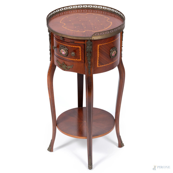 Comodino ad un cassetto impiallacciato e intarsiato in varie essenze con piano circolare e gambe mosse raccordate da pedana circolare, XX secolo, cm 68,5x34,5