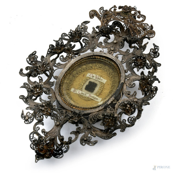 Ex voto con struttura in argento finemente cesellato a girali, XX secolo, cm 16x11, peso lordo complessivo gr 115 (segni di usura, difetti)