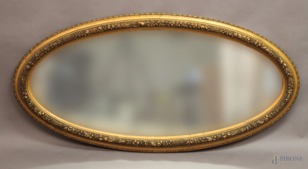 Specchiera di linea ovale in legno dorato, inizi XX sec., cm 135x64.
