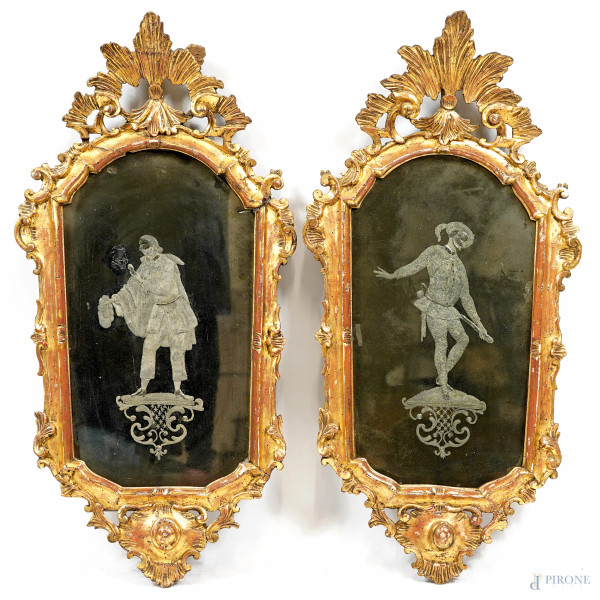 Coppia di specchierine con cornici in legno dorato e intagliato a tralci fogliacei a formare simmetricamente la ricca cimasa, specchi incisi con figure di Pulcinella e Arlecchino, XIX secolo, cm 77x39, (difetti)