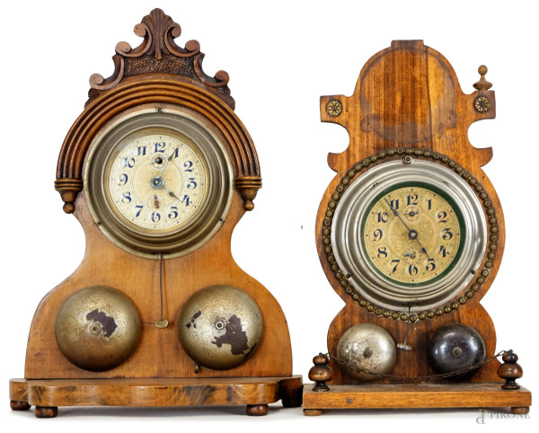Due orologi sveglia, inizi XX secolo, struttura in legno di linea sagomata, quadrante circolare a numeri arabi, cm h 34,5, (difetti, mancanze, meccanismi da revisionare).