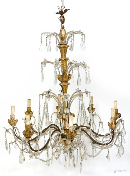 Lampadario in legno dorato ad otto luci, XVIII secolo, fusto e bracci intagliati a motivi floreali con pendenti in cristallo, cm h 114x82, (difetti, mancanze).