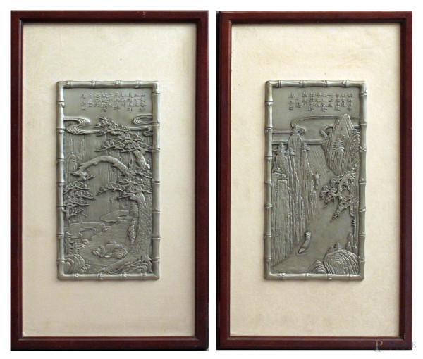 Coppia di placche in metallo a soggetto di paesaggi orientali con figure, cm 28 x 14, entro cornice.