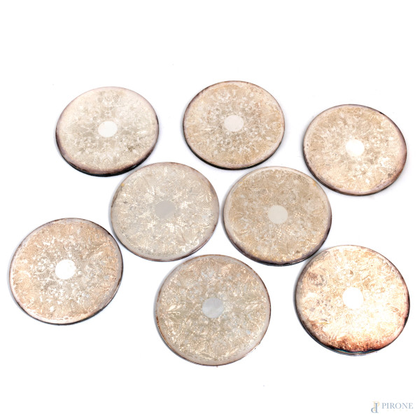Lotto di otto sottopiatti rivestiti in lamina di metallo argentato finemente cesellato, XX secolo, diametro cm 18, (segni di usura)