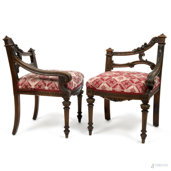 Coppia di poltroncine ad angolo in legno intagliato e seduta imbottita e rivestita in tessuto nei toni del bianco e del porpora, XX secolo, cm 76x50x48, (segni di usura, scalfiture)