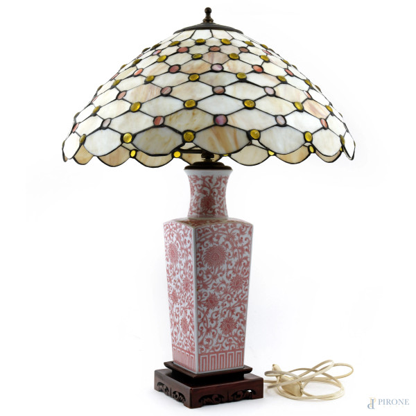 Lampada da tavolo con fusto in porcellana dipinta a motivi floreali nei toni del rosa con base in legno. Paralume in stile Tiffany con tessere policrome in pasta vitrea, altezza cm 69 (da revisionare)