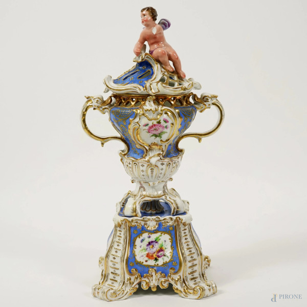 Potiche in porcellana blu e bianca con decori floreali e finiture dorate, coperchio sormontato da putto, XX secolo, h cm 31 (difetti, parte rotta)