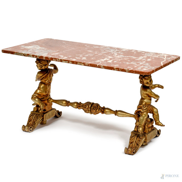 Tavolinetto in legno intagliato e dorato con piano rettangolare in marmo, due gambe a foggia di putti raccordate da traversa, XX secolo, cm 57x105x54,5, (difetti)