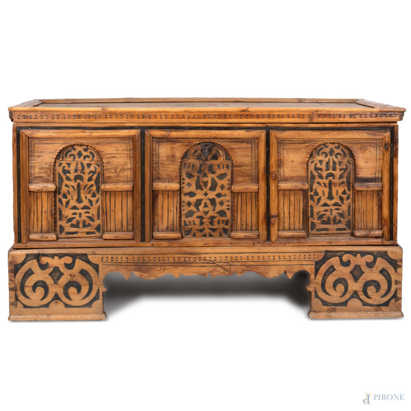 Cassapanca in legno con fronte decorato ad intaglio tripartito in tre pannelli. Piano apribile a ribalta celante vano unico. Piedi a mensola. XVIII-XIX secolo, cm 80x150x63, (segni di usura, graffi, scalfiture, difetti)