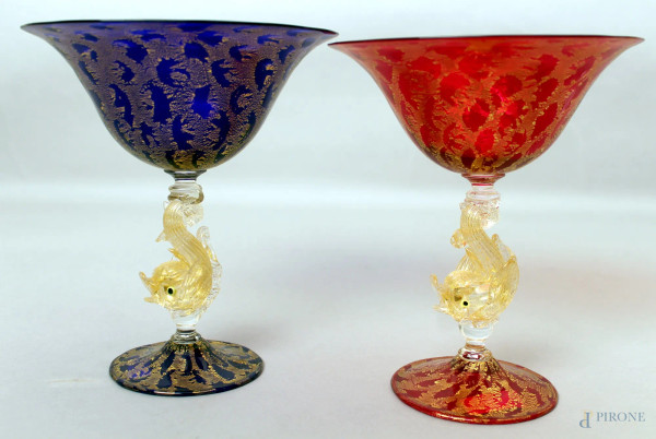 Coppia di calici in vetro di Murano rosso e blu retti da tritoni, particolari dorati, H 20 cm.