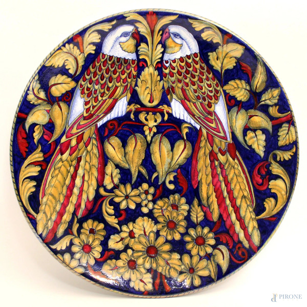 Piatto in maiolica smaltata e dipinta a soggetto di volatili e fiori, marcato Remigi Gualdo Tadino, diametro 36 cm.