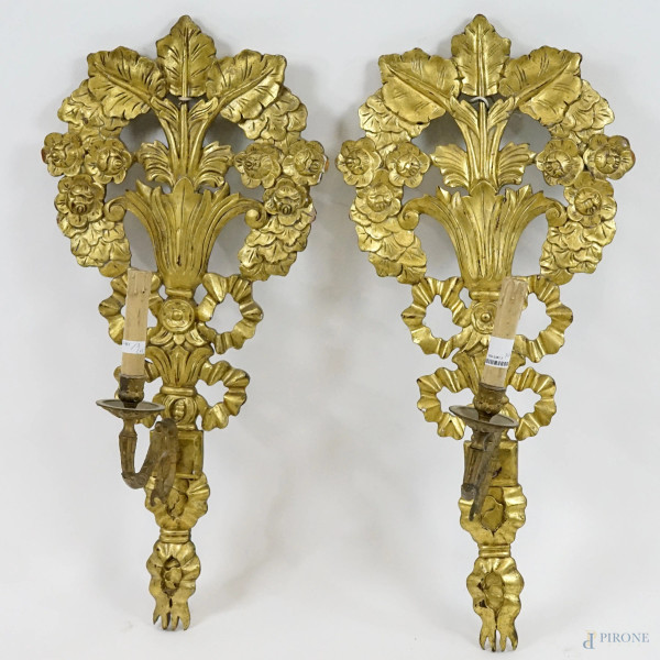 Coppia di appliques in legno intagliato a palmette, motivi floreali e nastri, braccia a volute in metallo dorato, cm 79x37, (difetti)
