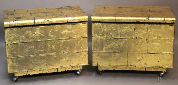 Coppia di piccoli mobilini a tre cassetti in legno laccato e dorato poggianti su rotelle, cm 56 x 70 x 43.