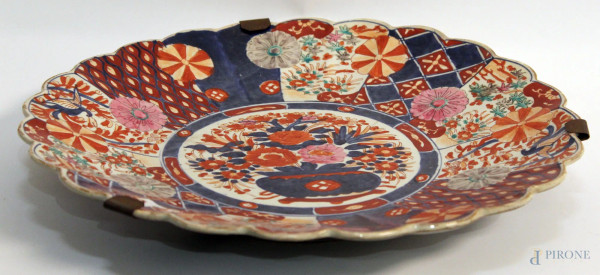 Piatto in porcellana Imari a decoro floreale e motivi geometrici, XIX sec., diametro cm 43.
